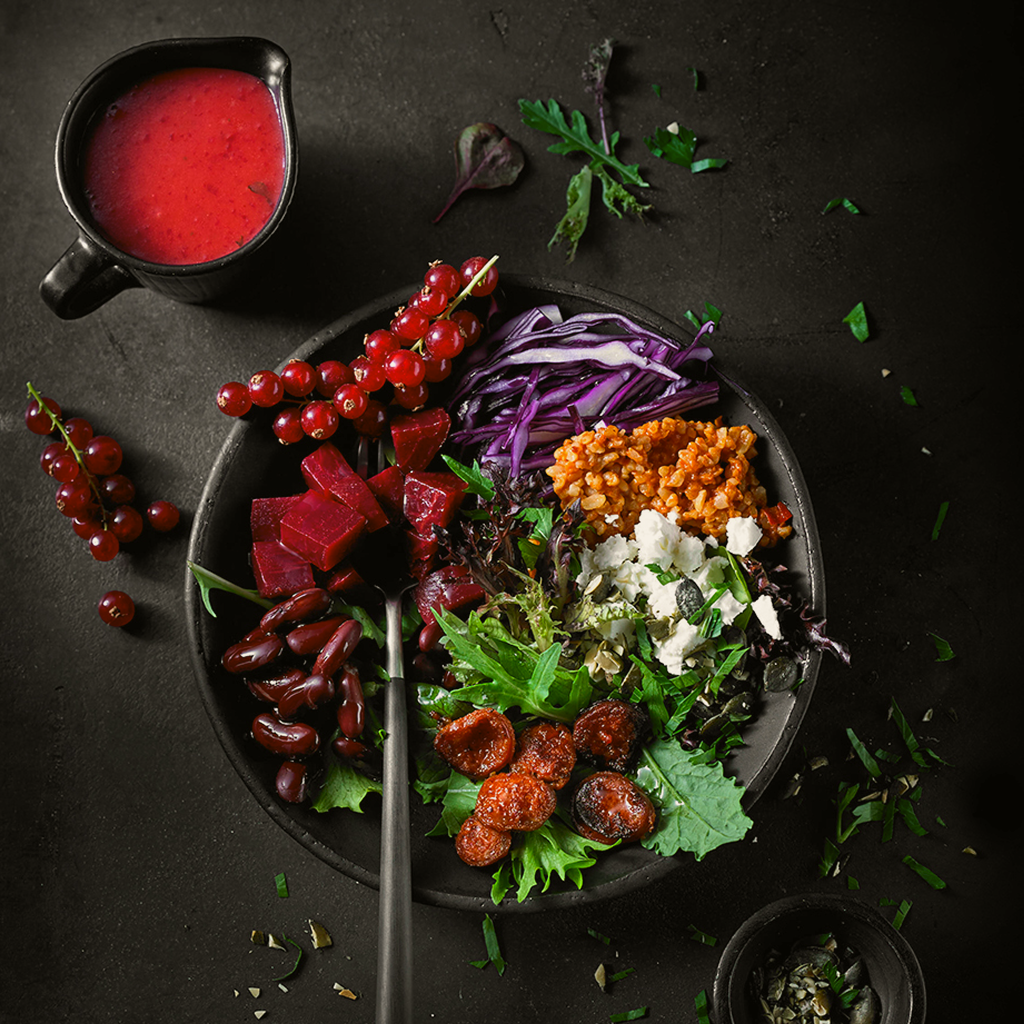 Frisch angerichtete Red Bowl Creation mit knackigem Gemüse, Getreidebasis, roten Toppings und aromatischer Sauce in einer Buddha Bowl serviert.